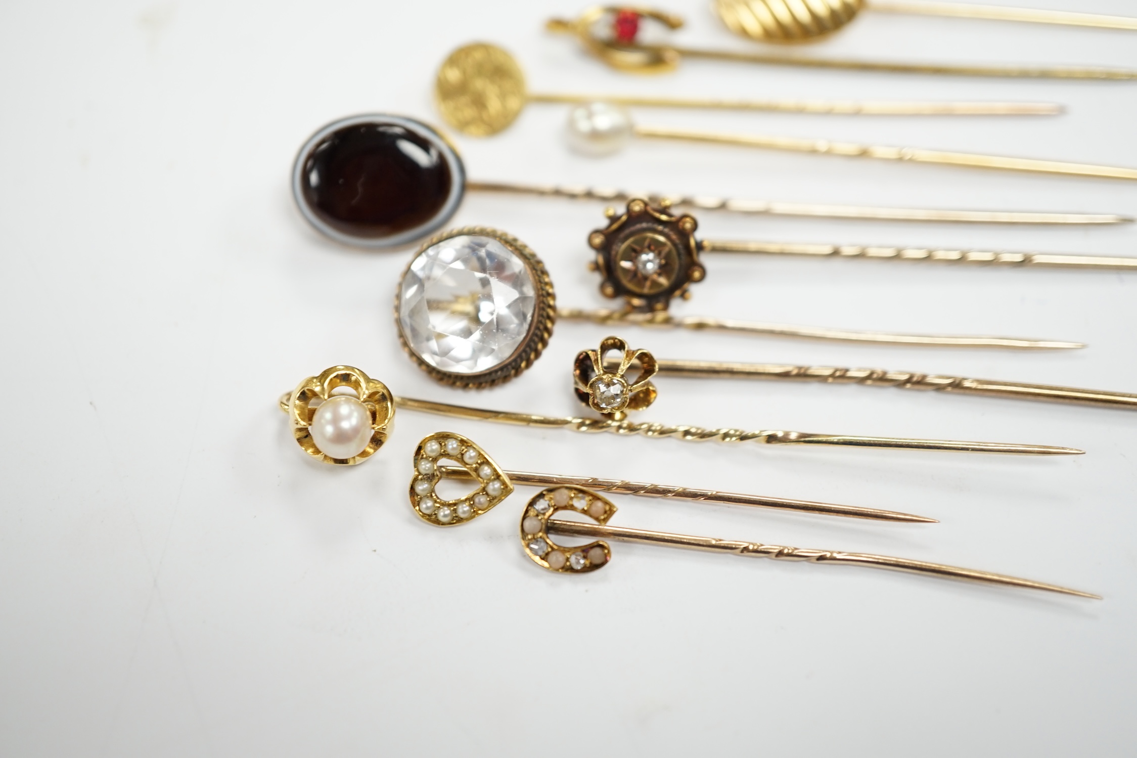 Fifteen assorted mainly early 20th century yellow metal and gem set stick pins, including diamond, seed pearl and banded agate, gross weight 23.1 grams.